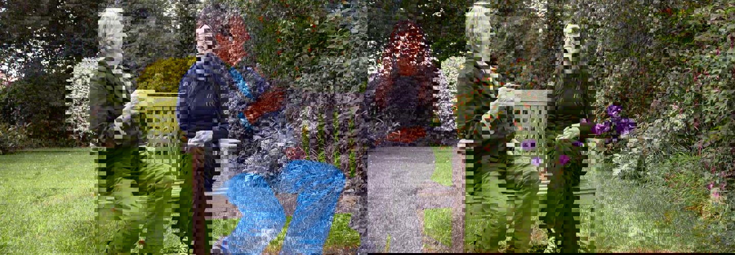 CareGiver and Parkinson's Client laughing on bench