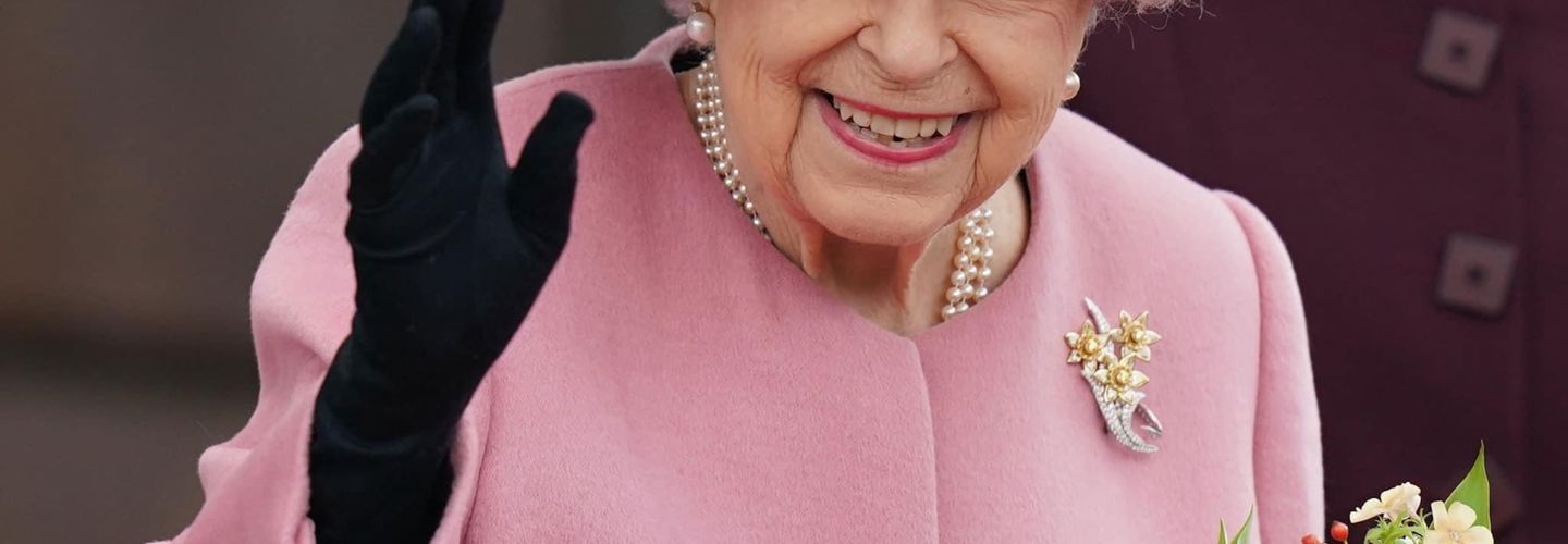 Image of Queen Elizabeth II wearing a pink dress and holding flowers in left hand