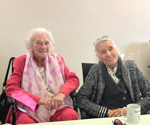 Two elderly ladies smile looking at the camera